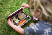 Child grabbing food from stainless leak proof lunchbox 