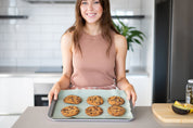 Green Reusable Baking Mat on a tray with cookies and woman smiling